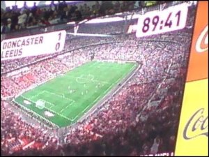 One of the Wembley big screens shows the score with just seconds of normal time left to play
